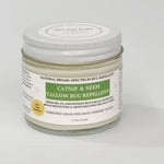 A jar of catnip and neem tallow bug repellent by The Cat Lady, featuring a white lid and a white label with green and gold accents, set against a plain light gray background.