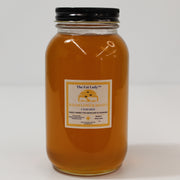 Wildflower raw honey jar from The Fat Lady with a golden honey color, labeled for skincare and cooking, in a natural setting.