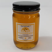 Wildflower raw honey from The Fat Lady, showing a jar of unfiltered honey with a honey dipper on a wooden surface.