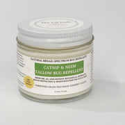 A jar of catnip and neem tallow bug repellent by The Cat Lady, featuring a white lid and a white label with green and gold accents, set against a plain light gray background.