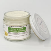 A jar of catnip and neem tallow bug repellent with its lid leaning against it on a clean white background. The product is in a clear glass jar showing the off-white cream inside, with a white label featuring green and black text.